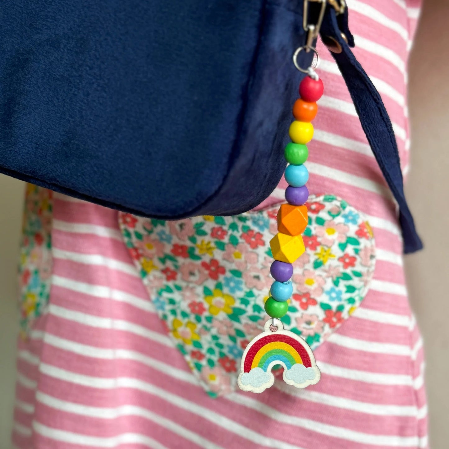 Colorful beaded charm with a rainbow design attached to a blue bag.
