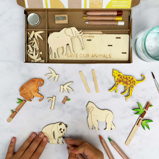 Wooden animal cutouts with 'Save Our Animals' message on a table with coloring supplies.