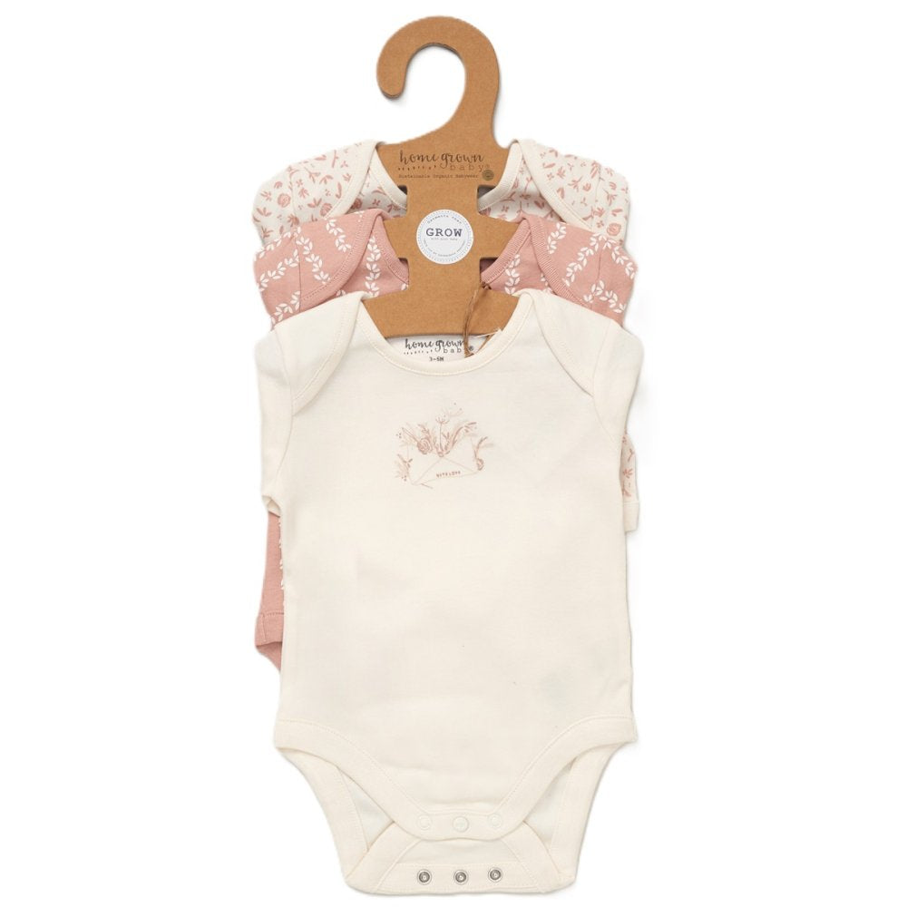 Floral baby vests on a hanger against a white background