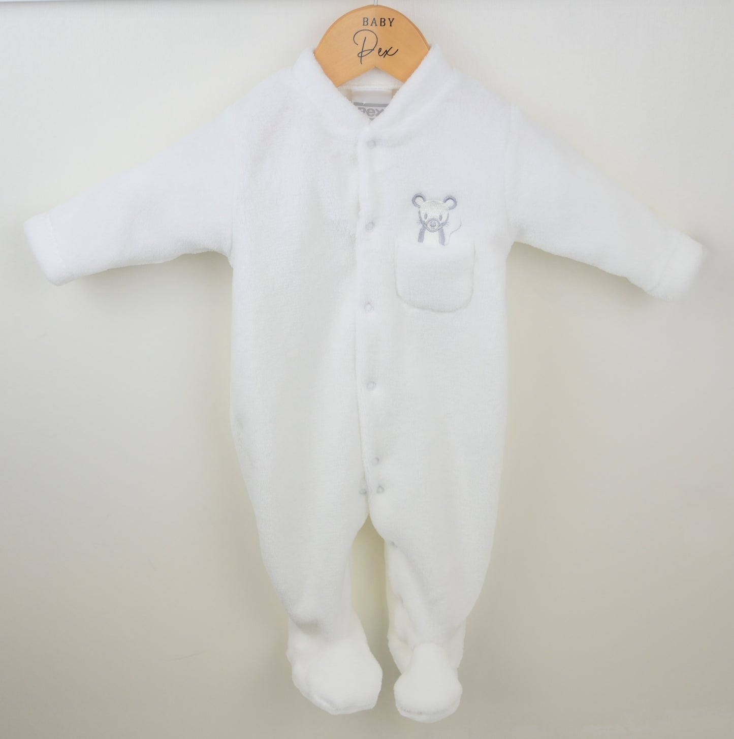 White baby onesie with a mouse emblem on a beige background
