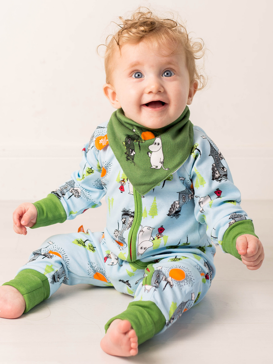Baby wearing a colorful outfit with moomin patterns on a plain background