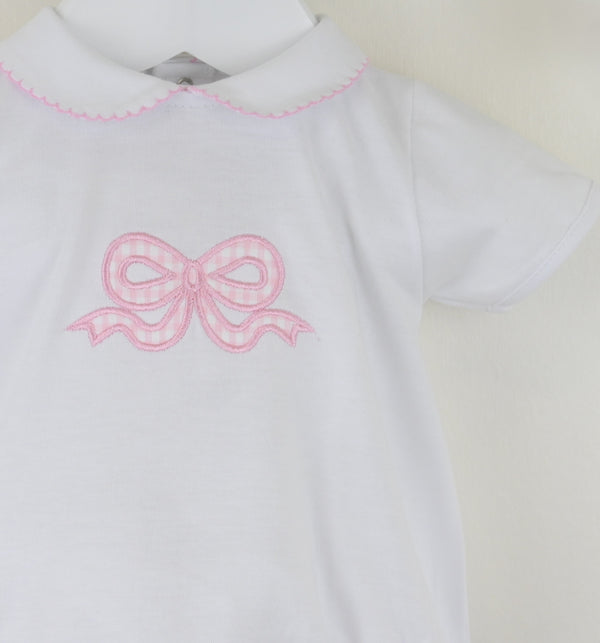 White garment with pink embroidered bow on a plain background