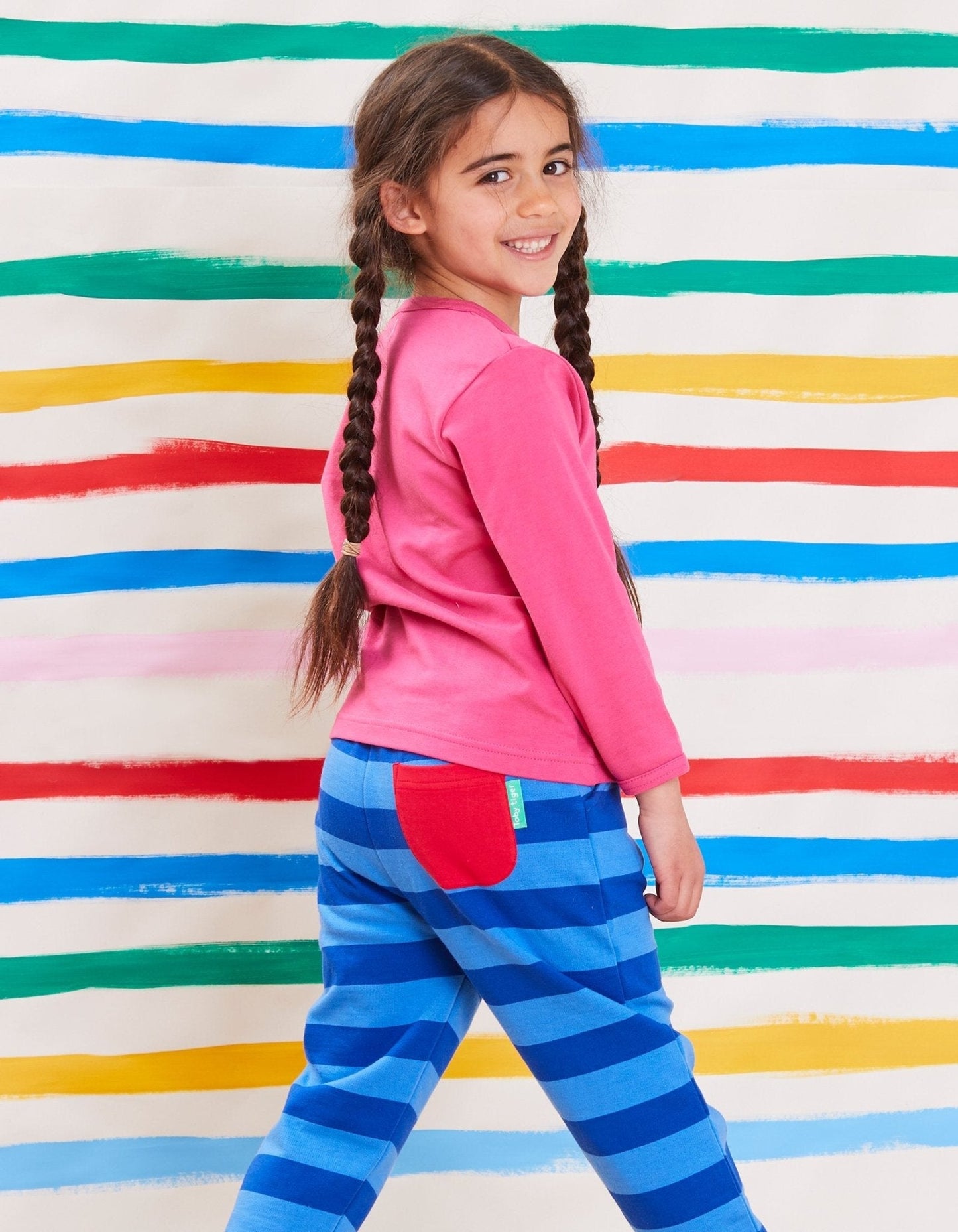 Young girl in pink top and blue striped organic joggers by Toby Tiger.