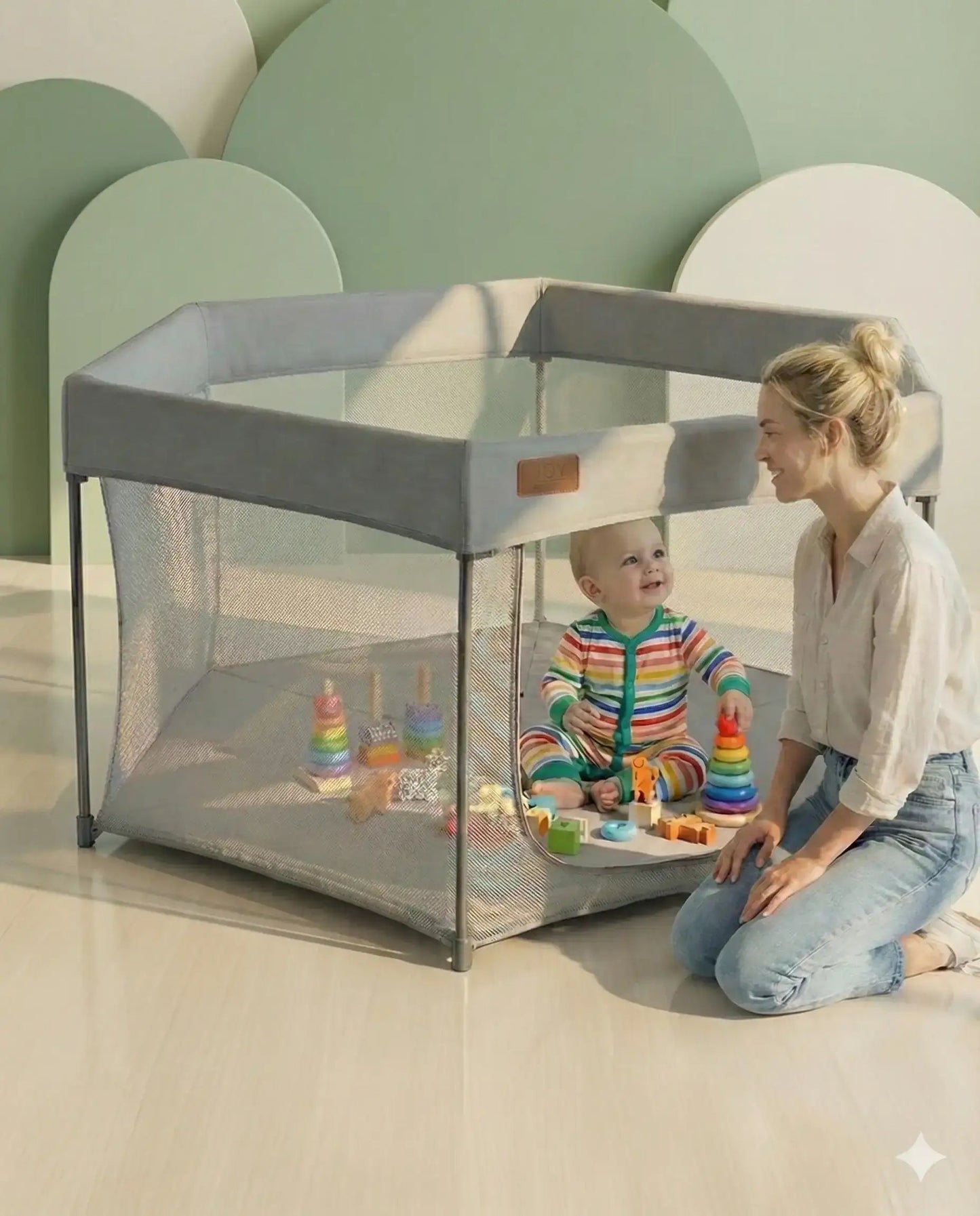 Woman and child playing with toys inside a portable playpen in a minimalistic room.