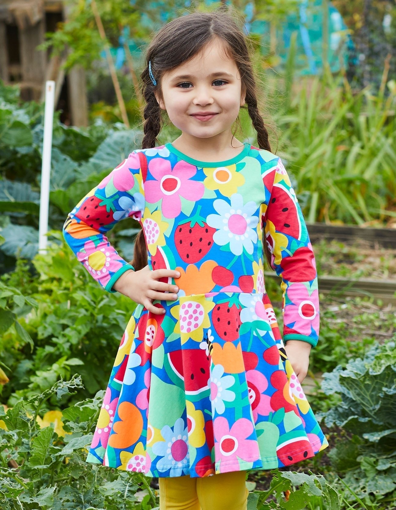 Young girl wearing a colorful dress with fruit patterns in an outdoor setting