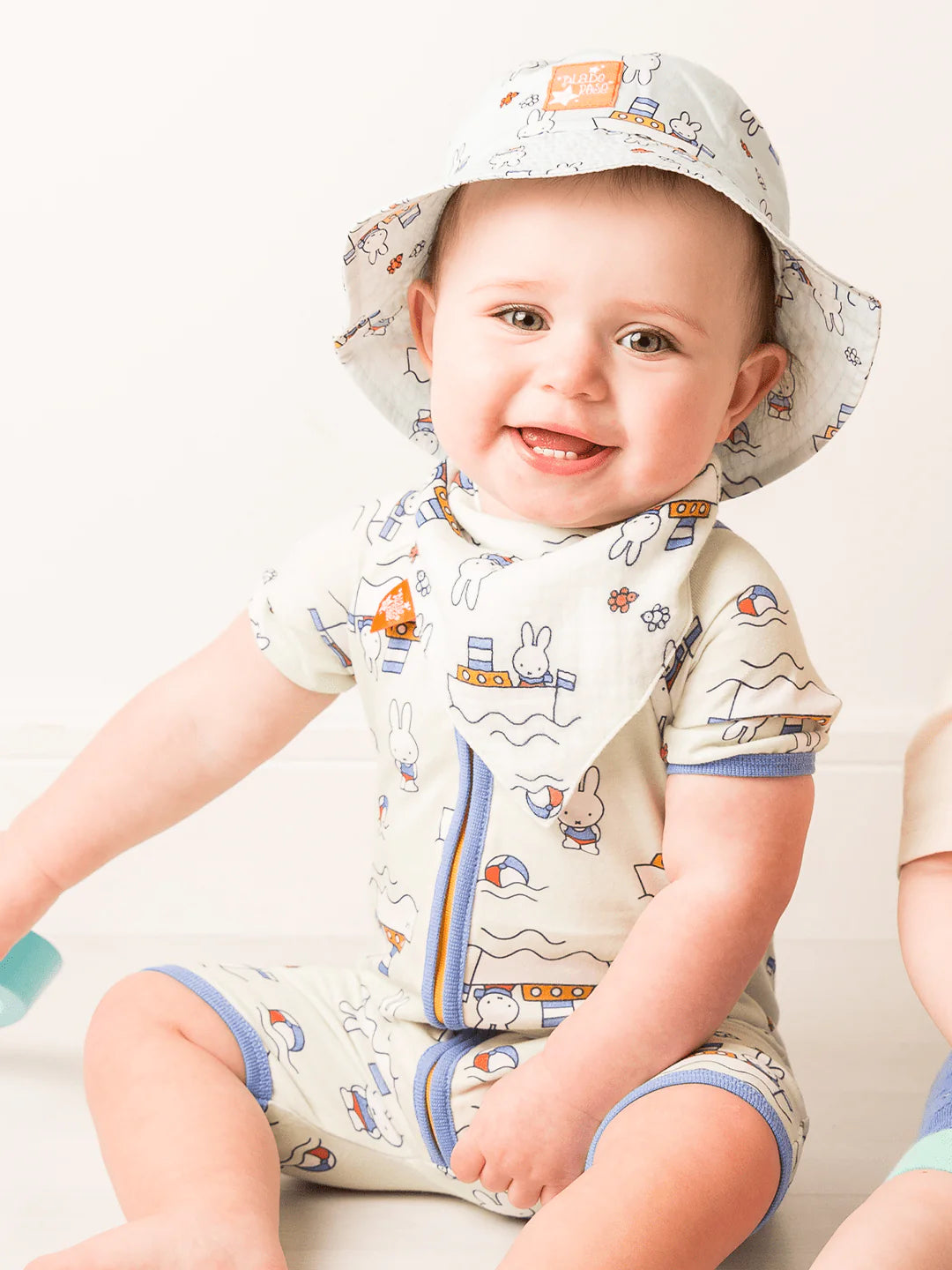 Baby wearing a Miffy romper, hat and matching bib.