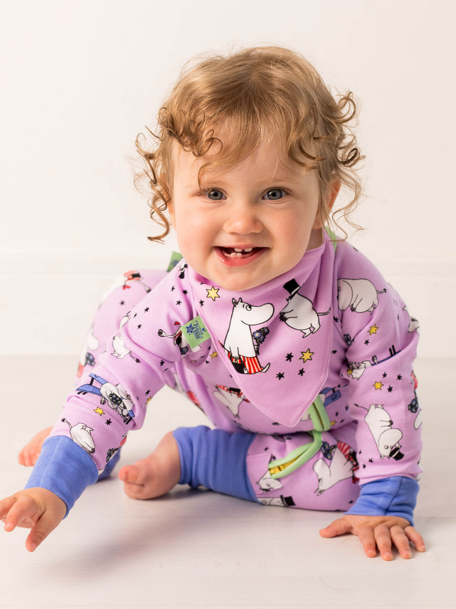 Child wearing a purple pajama set with Moomin characters on a white background