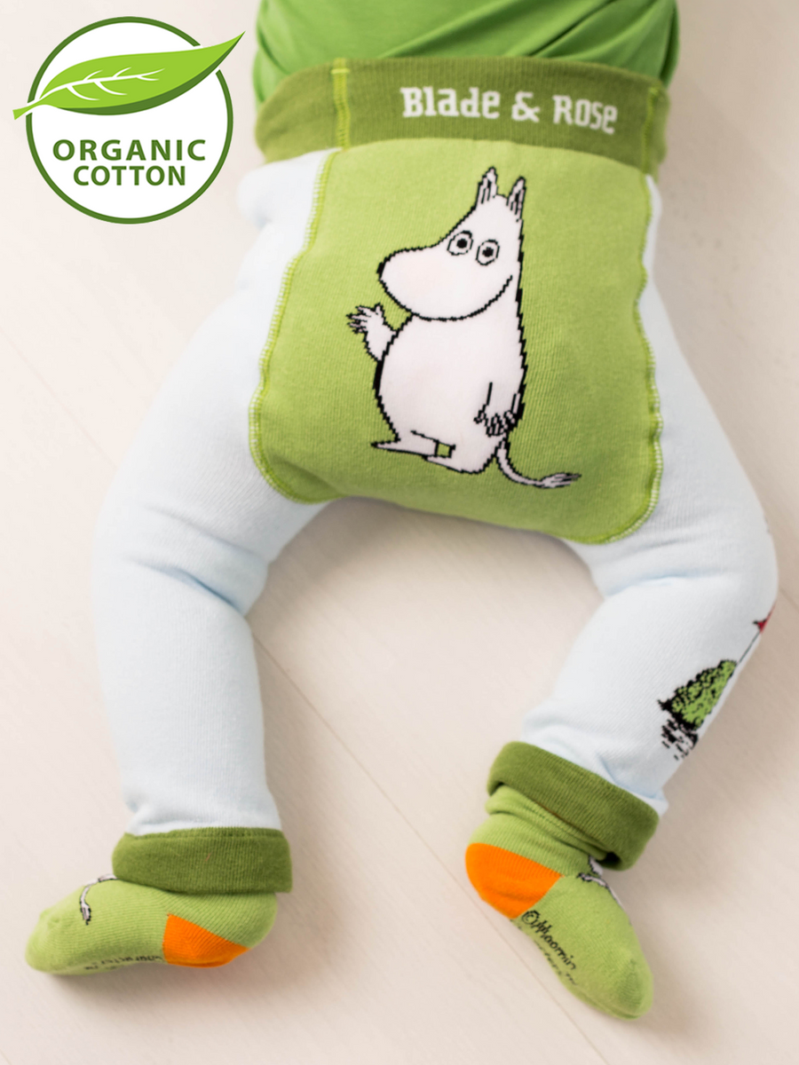 Baby wearing green organic cotton leggings and socks with Moomin cartoon character, on a light background