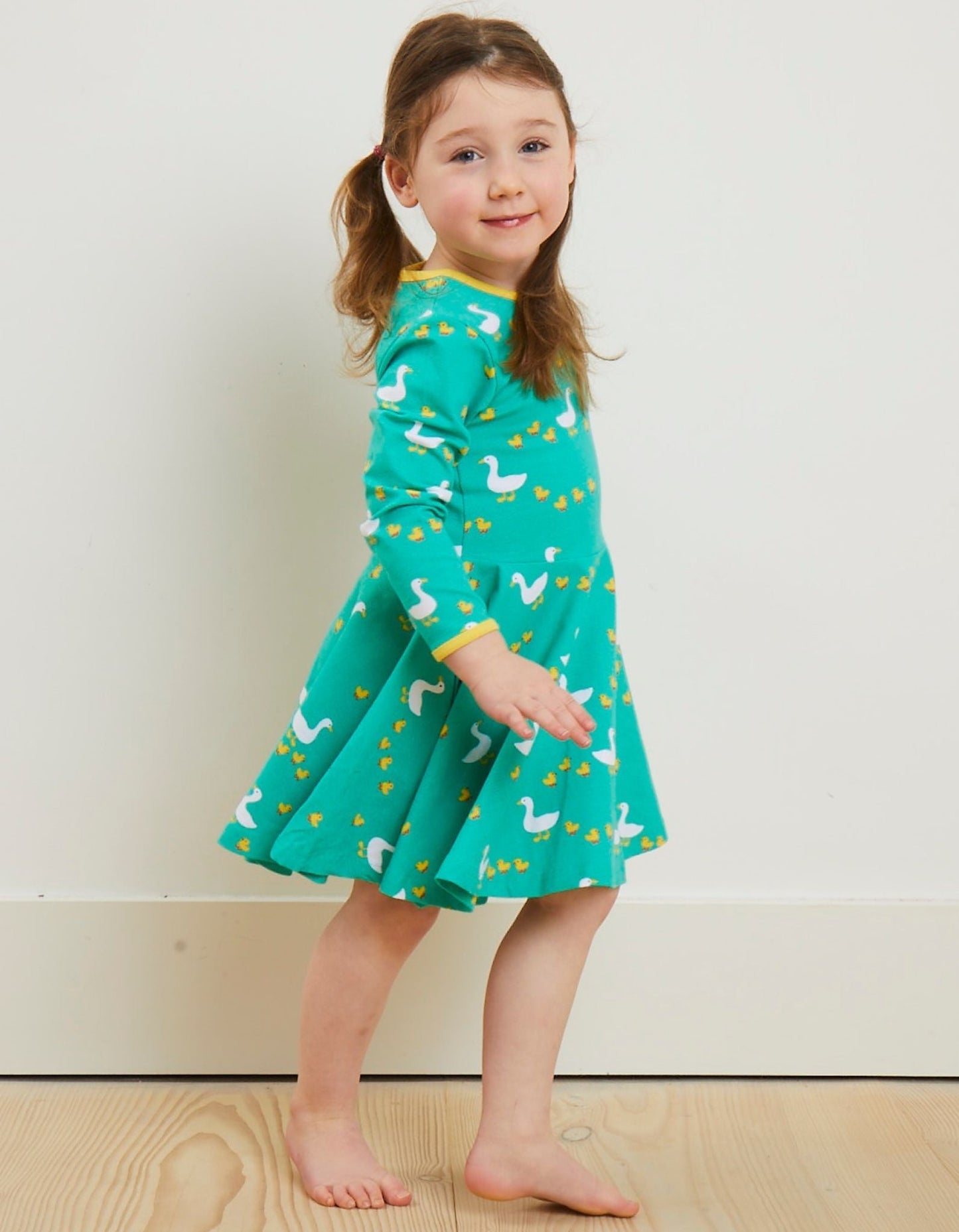 Young girl wearing a green dress with animal patterns on a plain background