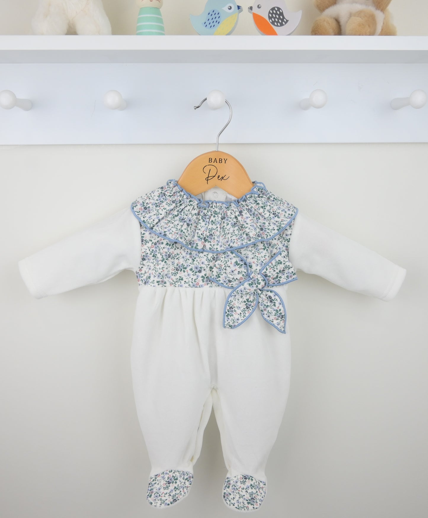 White baby romper with floral top on a hanger against a white background