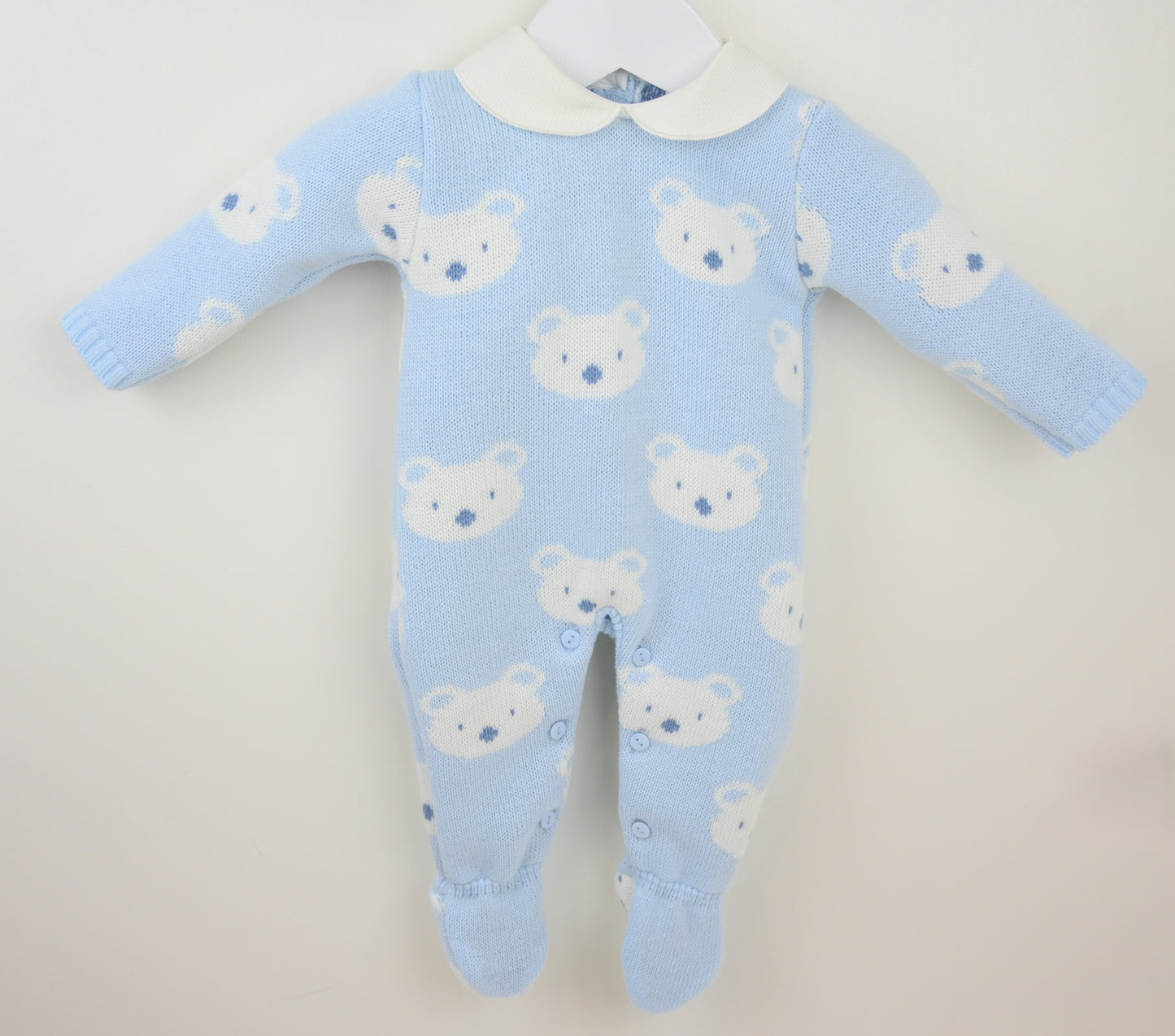 Blue baby onesie with bear pattern on a beige background