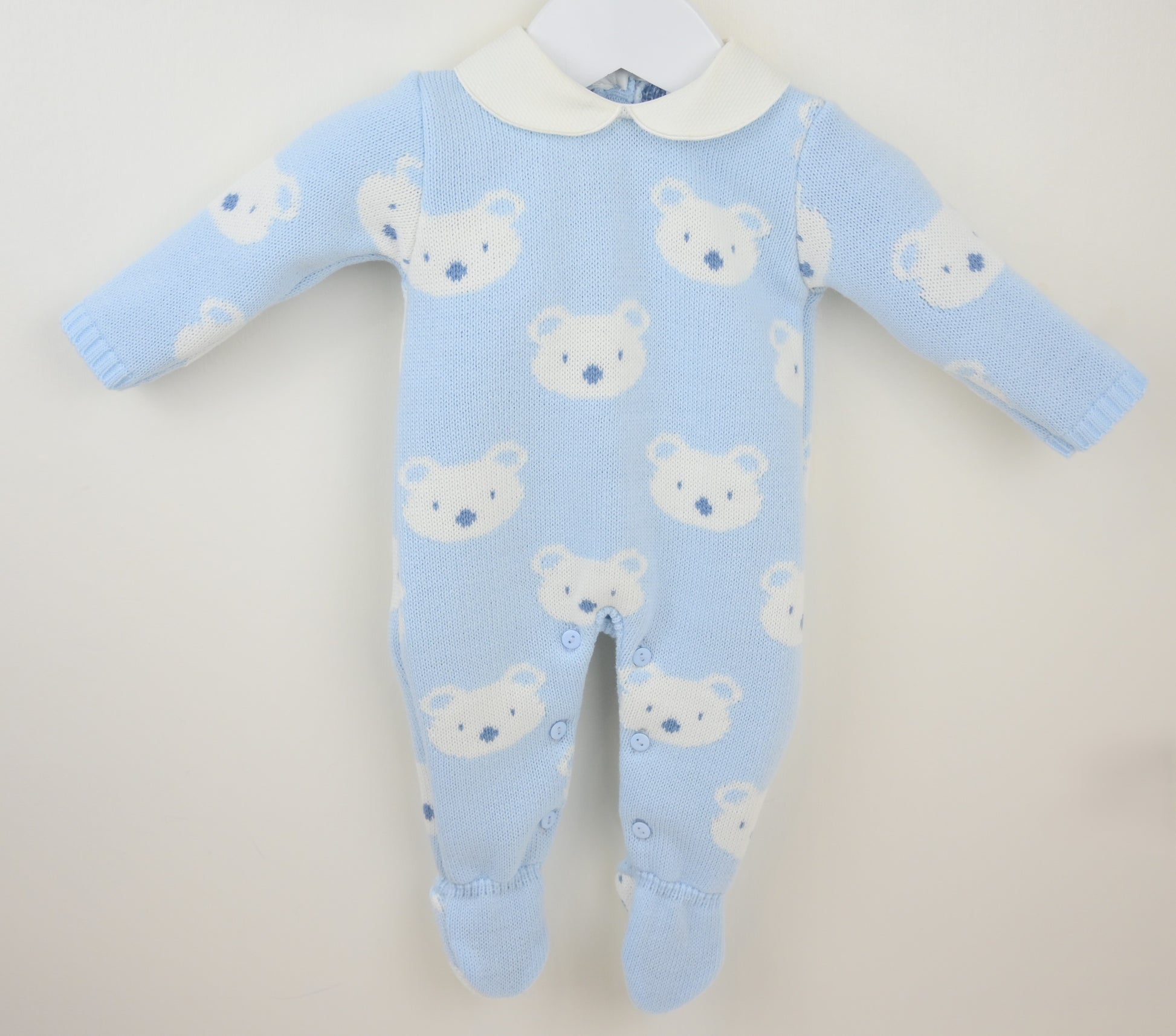 Blue baby onesie with bear pattern on a beige background
