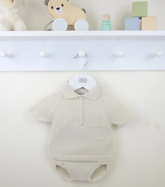 Knitted baby 2 piece outfit on a hanger with toys in the background