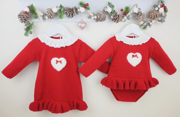 Two red baby outfits with white hearts and bows on a light background.