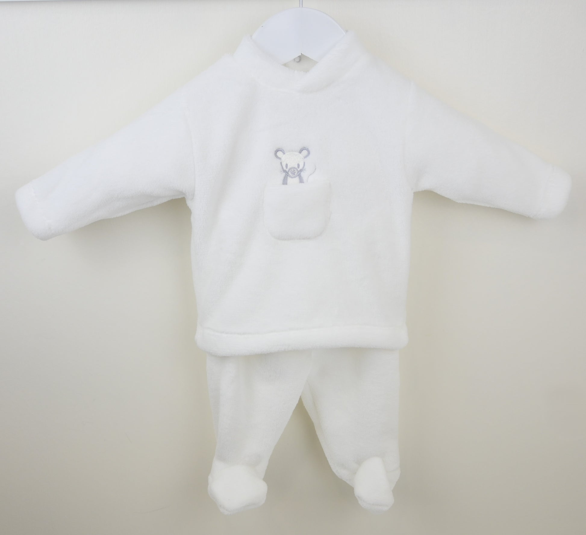 White baby outfit with a small mouse on a beige background