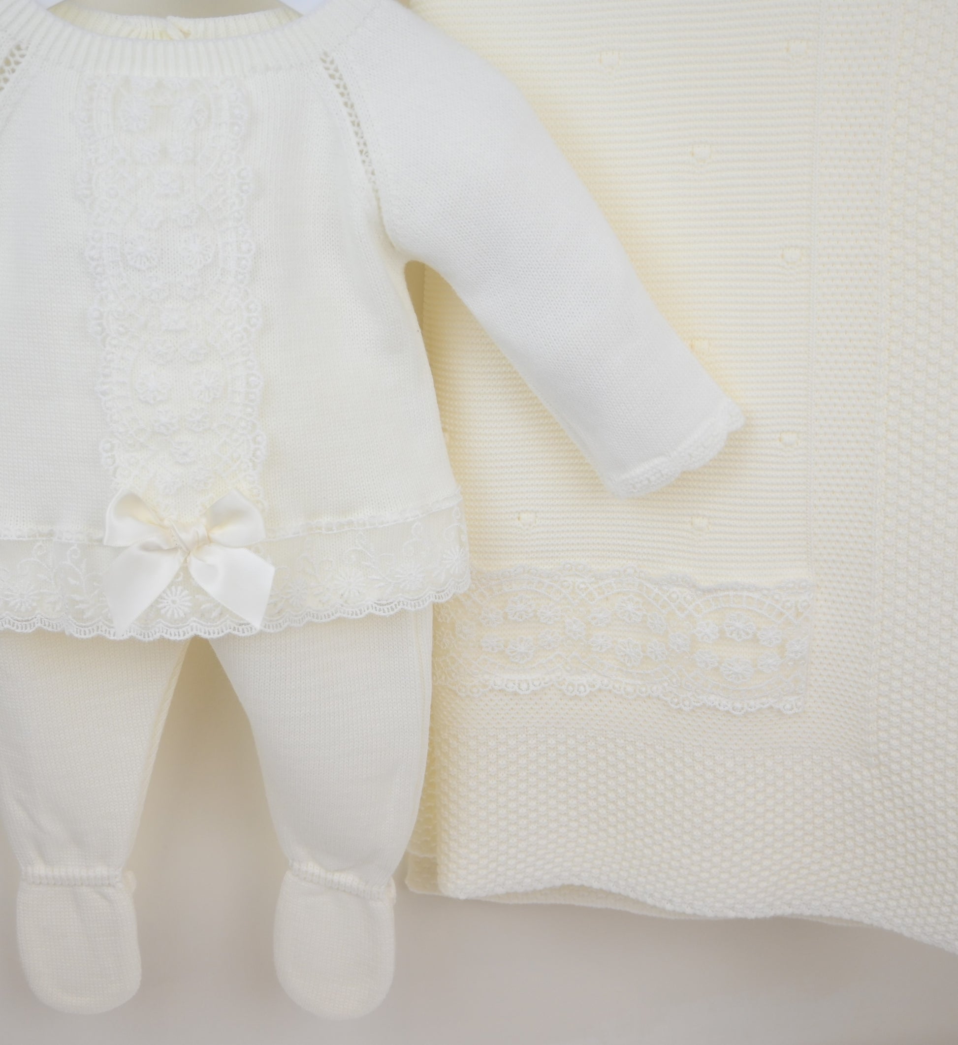 Ivory baby outfit with bottoms on a textured surface