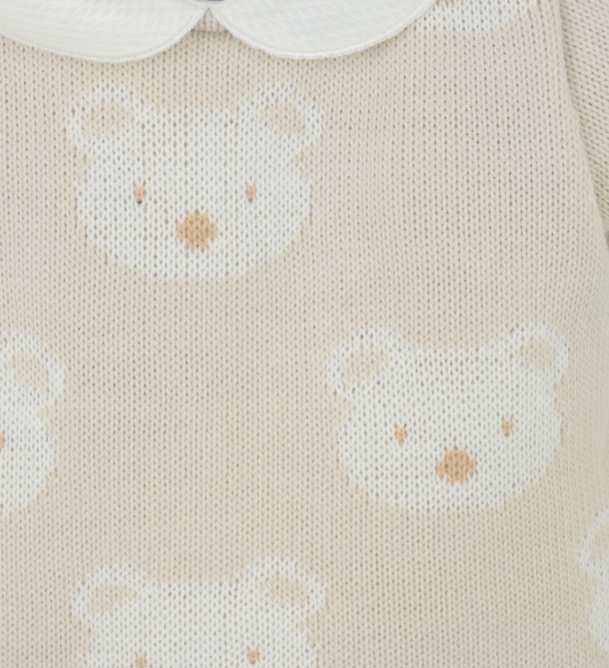 Close-up of knitted fabric with white bear patterns on a beige background
