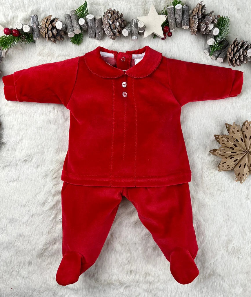 Red baby outfit on a white surface with Christmas decorations.
