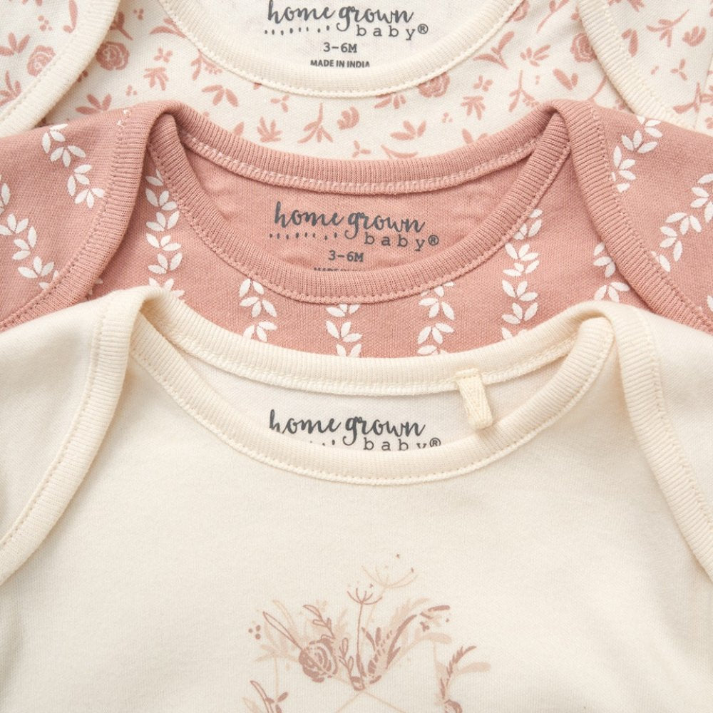 Close-up of baby clothing with 'homegrown baby' branding on a floral patterned background.