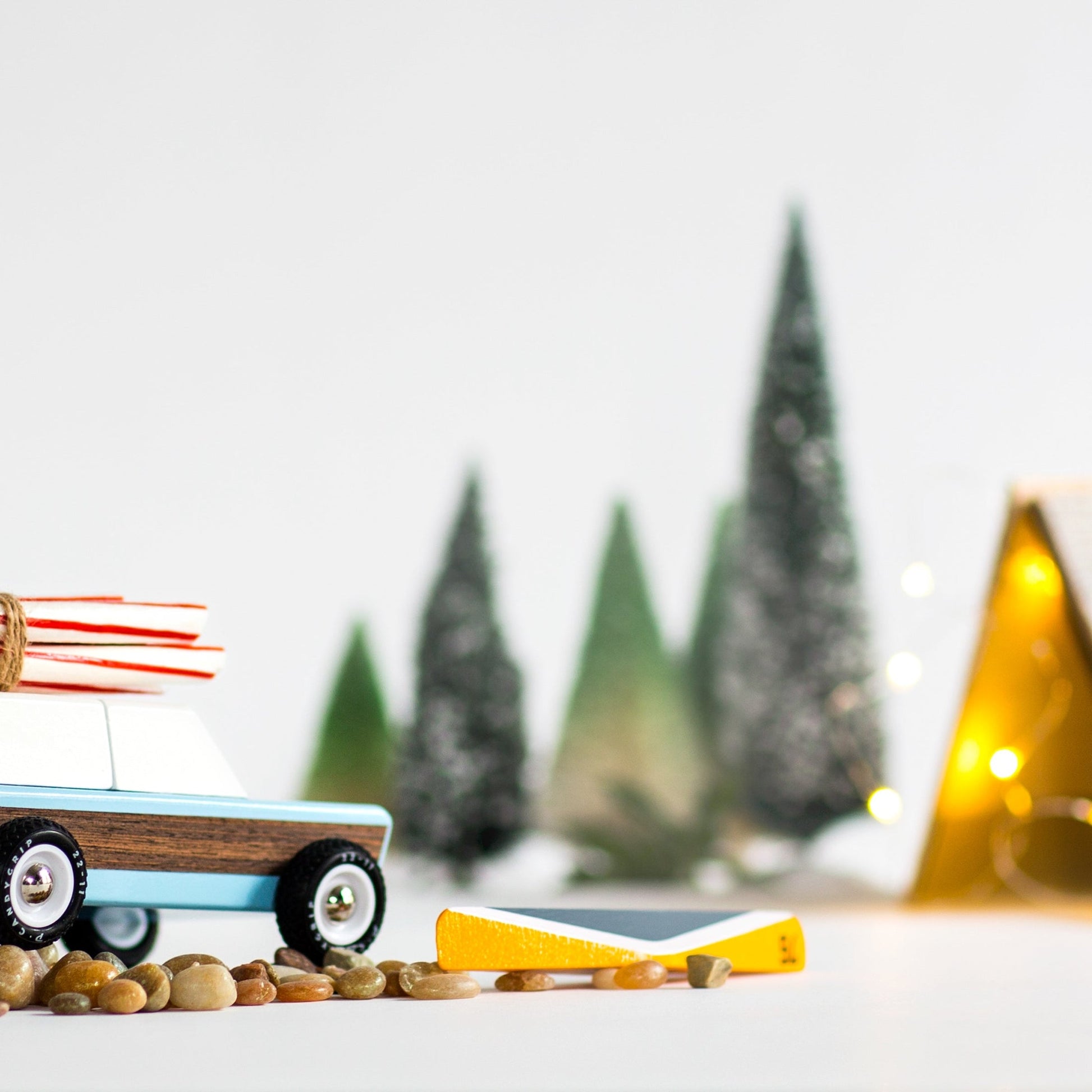 Toy cars on a snowy landscape with trees and a tent in the background