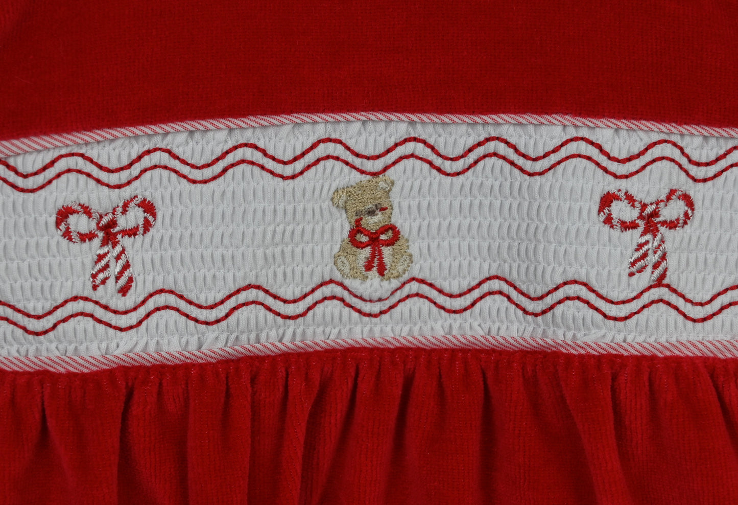 Red fabric with white embroidered border featuring teddy bears and candy canes.
