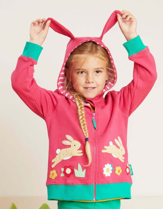 Child wearing a pink hoodie with bunny ears and rabbit designs on a plain background