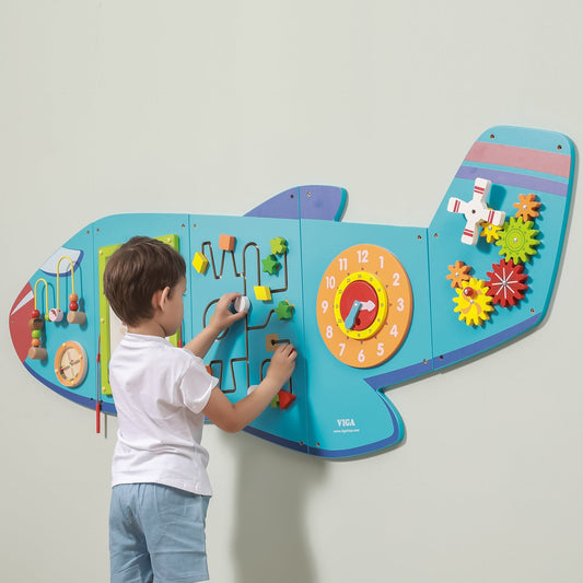 Child interacting with a colorful educational wall panel shaped like an airplane.