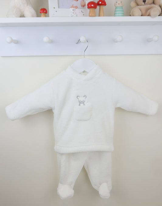 White baby outfit with a small mouse design on a hanger against a white wall.