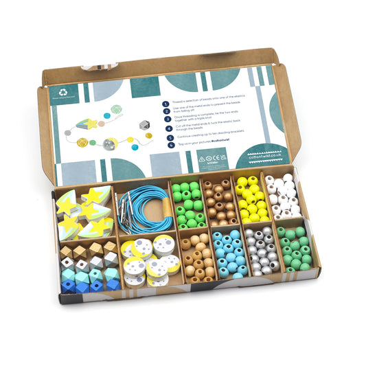 Open box containing a variety of colorful beads and craft materials on a white background