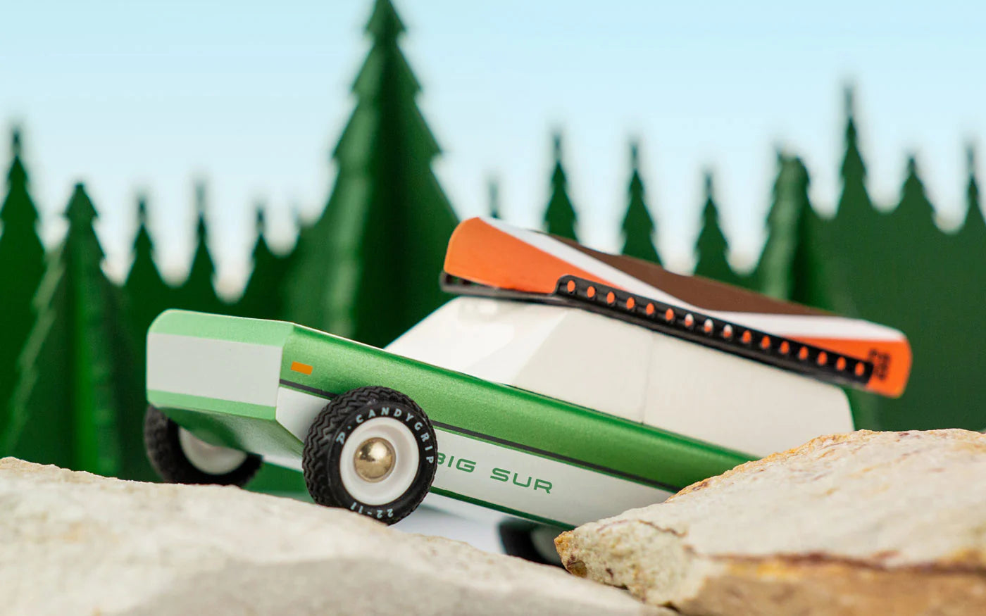 Candylab car in green with rocky trees background.