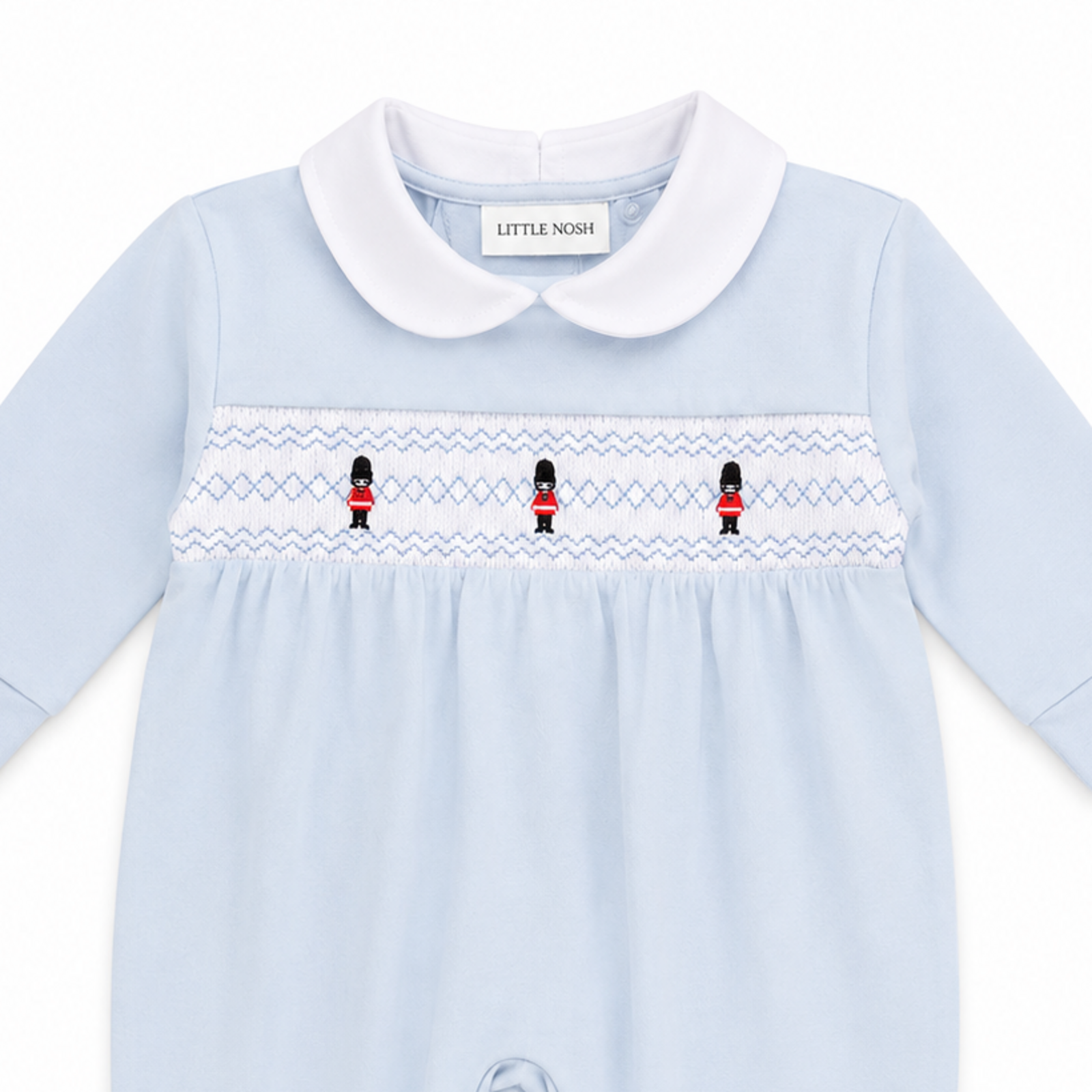 Smocked soldier embroidery detail on Little Nosh baby boys blue velour sleepsuit