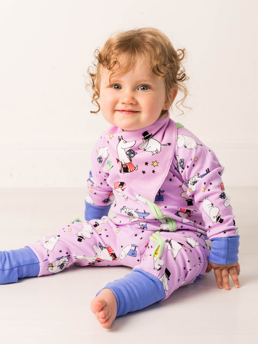 Child wearing purple Moomin romper with matching character bib.