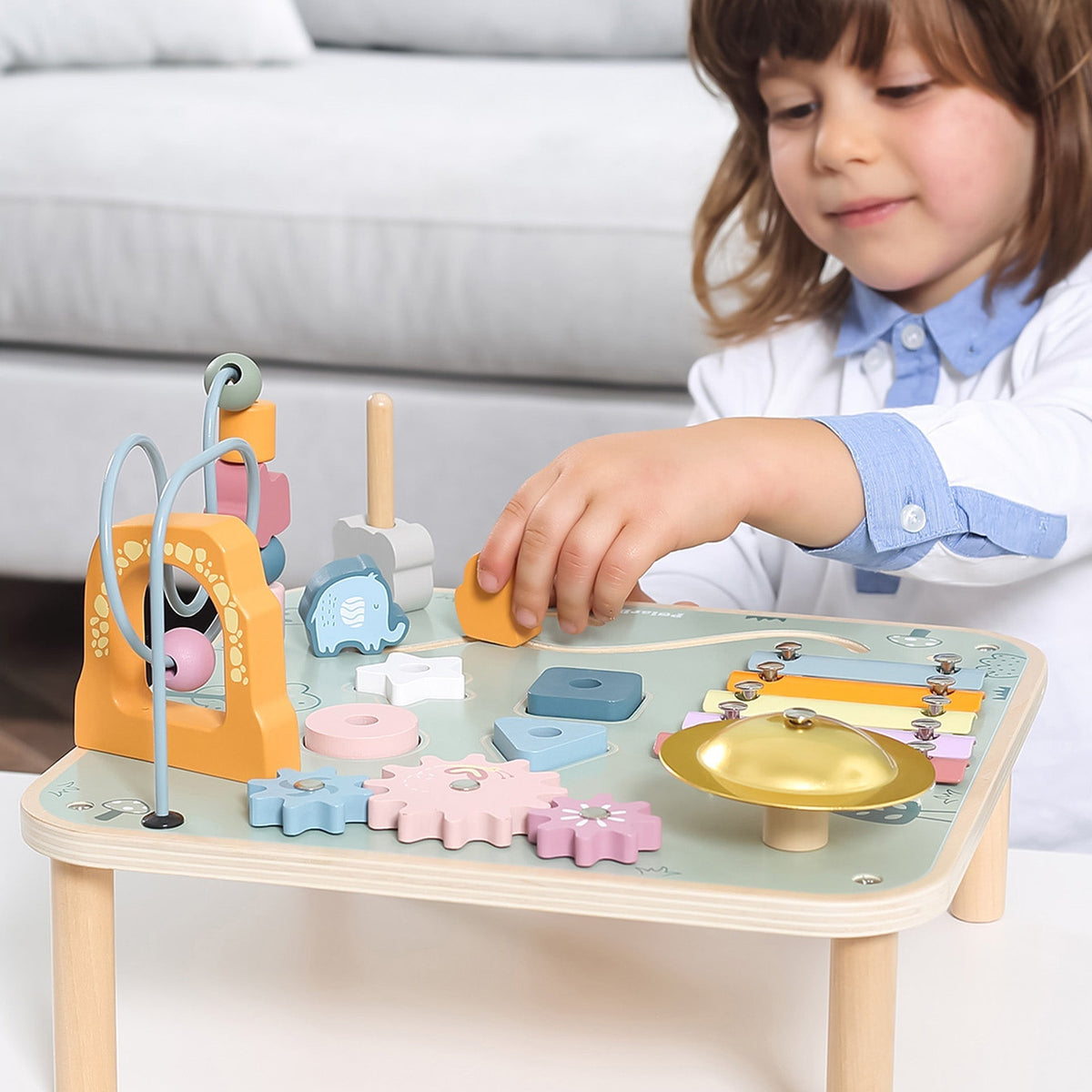 Close-up view of the sensory play elements on a traditional wooden activity table for children.